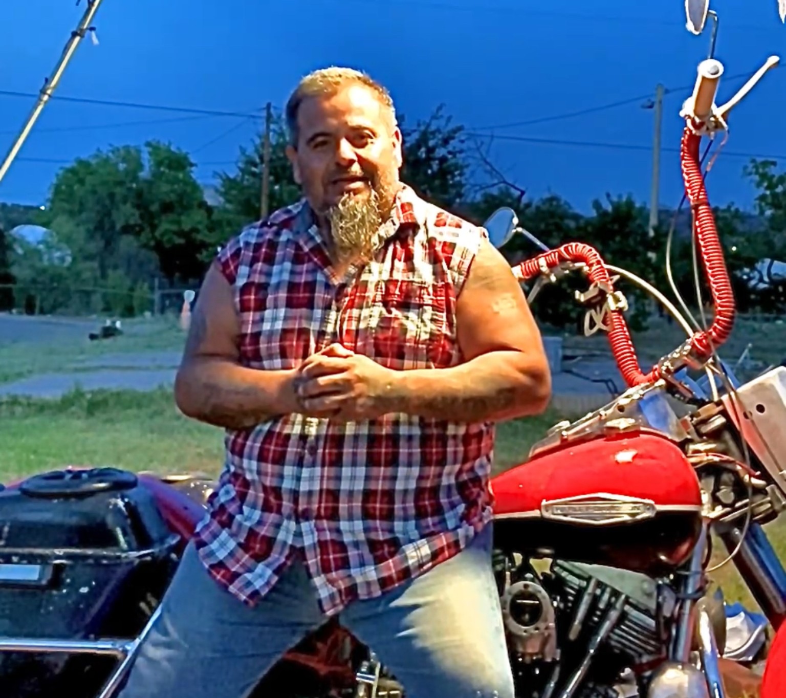 Preacher Joe sitting beside his red motorcycle